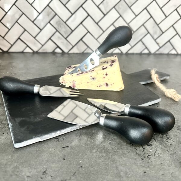slate cheese board with knives and a block of cheese