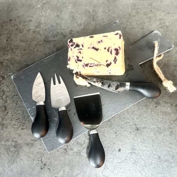 slate cheese board with knives and a block of cheese